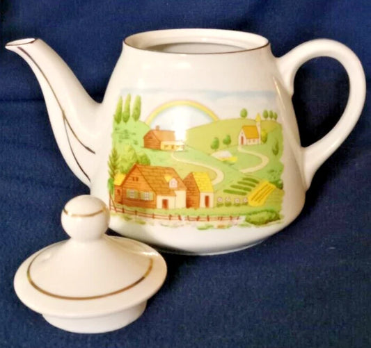 La tetera de cerámica vintage, fabricada en Japón, presenta un diseño de paisaje rural pintado a mano y un borde plateado. 11cm de alto 10cm diámetro.