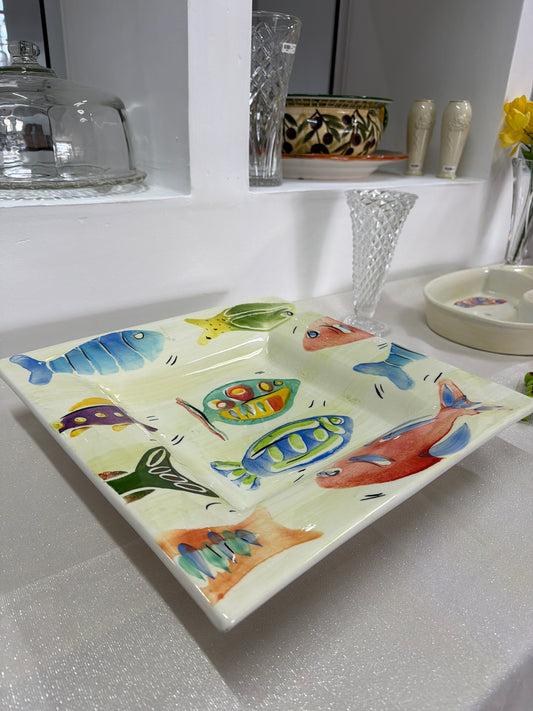 Fuente o plato cuadrada de cerámica artesanal italiana de 37 cm, decorada con ilustraciones de peces multicolores pintadas a mano.