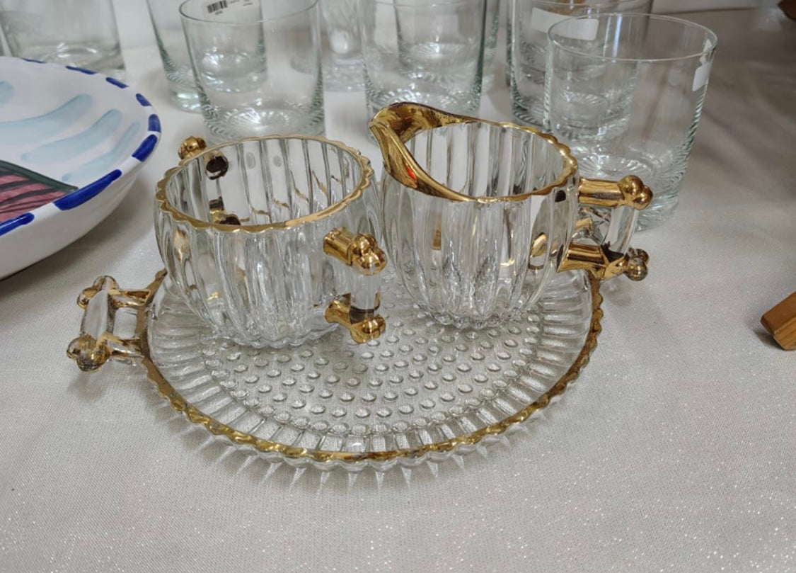 Este conjunto de 3 piezas incluye un plato, un azucarero y una cremera, todos con un elegante borde dorado.