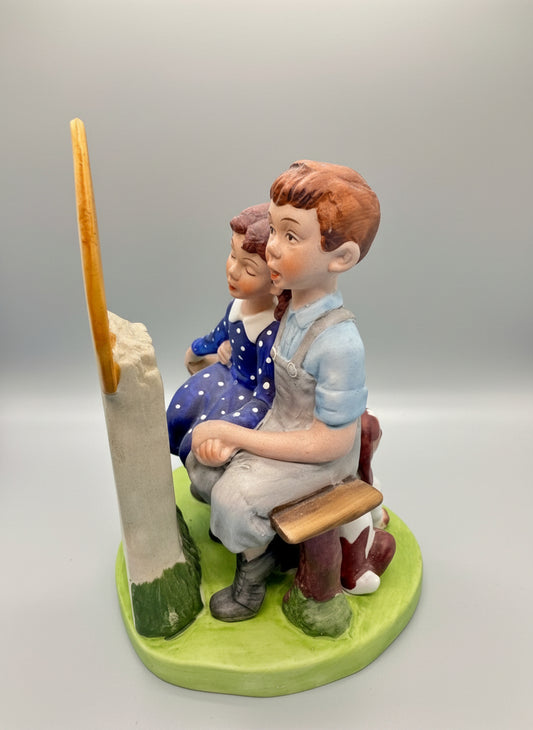 Norman Rockwell, La pieza representa a una pareja joven sentada en un banco, mirando a la luna, con un pequeño perro a su lado. Esta figura fue elaborada a mano en Japón.&nbsp;