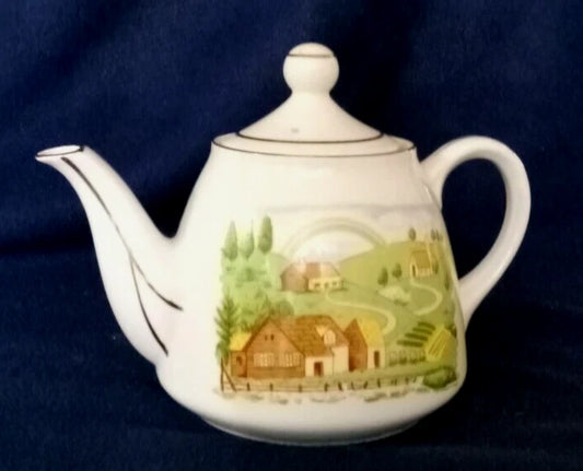 La tetera de cerámica vintage, fabricada en Japón, presenta un diseño de paisaje rural pintado a mano y un borde plateado. 11cm de alto 10cm diámetro.