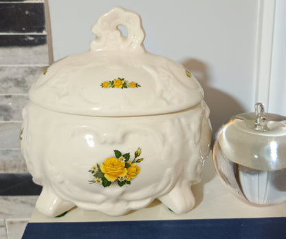 Joyero o bombonera de cerámica blanca presenta un diseño victoriano con relieve ondulado con rosas amarillas pintadas a mano. Medidas 17cm alto 10cm ancho de 13cm largo.