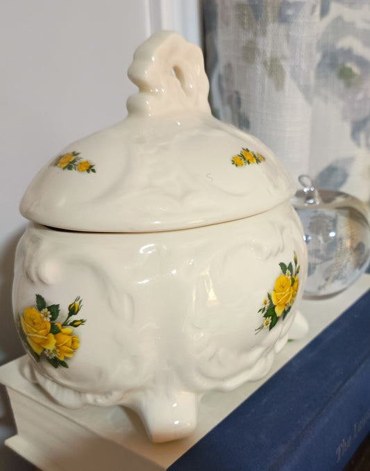Joyero o bombonera de cerámica blanca presenta un diseño victoriano con relieve ondulado con rosas amarillas pintadas a mano. Medidas 17cm alto 10cm ancho de 13cm largo.