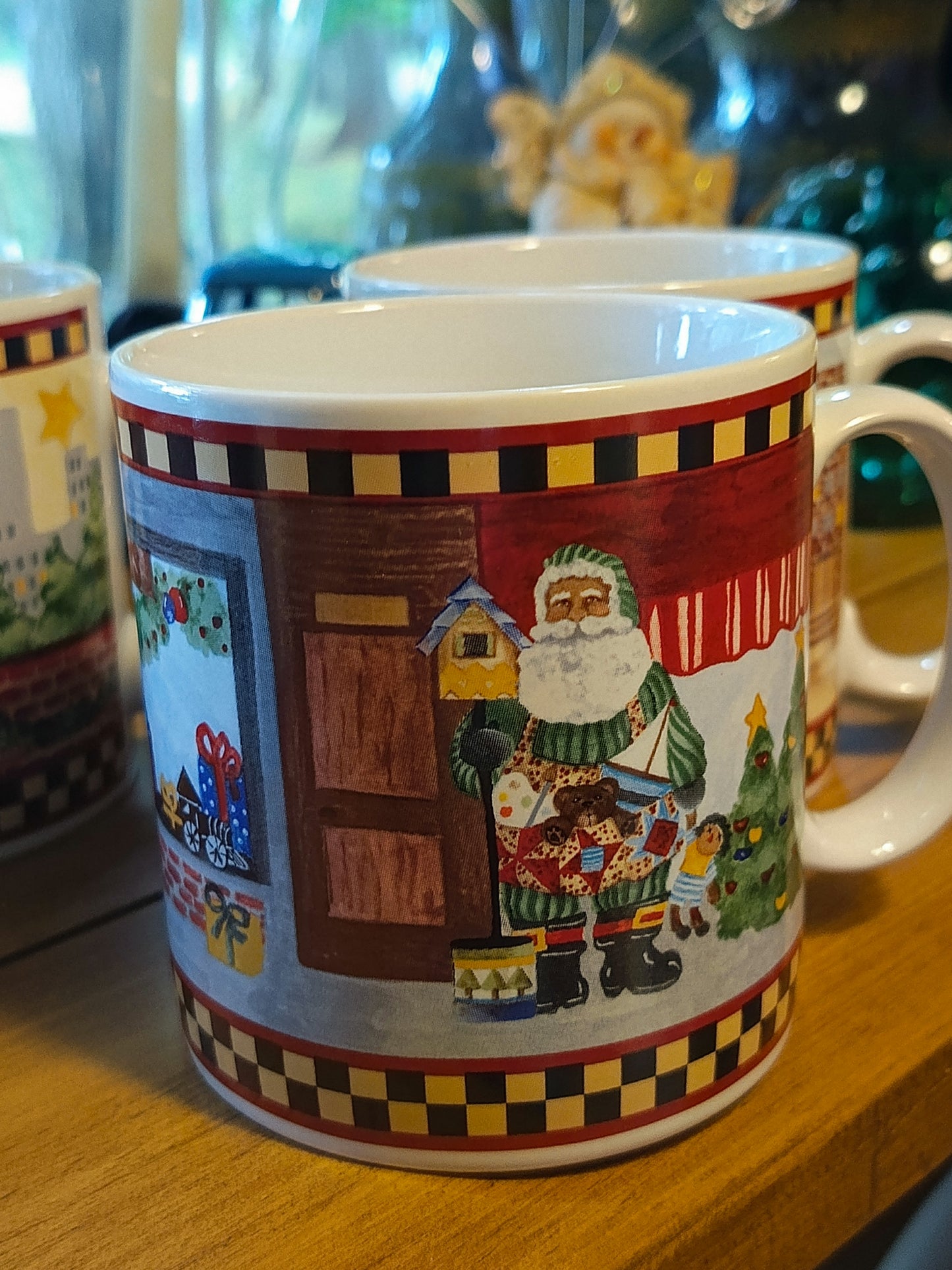Este set de 4 tazas navideña de café "Santa's Spirit" de Debbie Mumm para Sakura tiene una capacidad de 12 onzas y un diseño navideño con borde a cuadros.